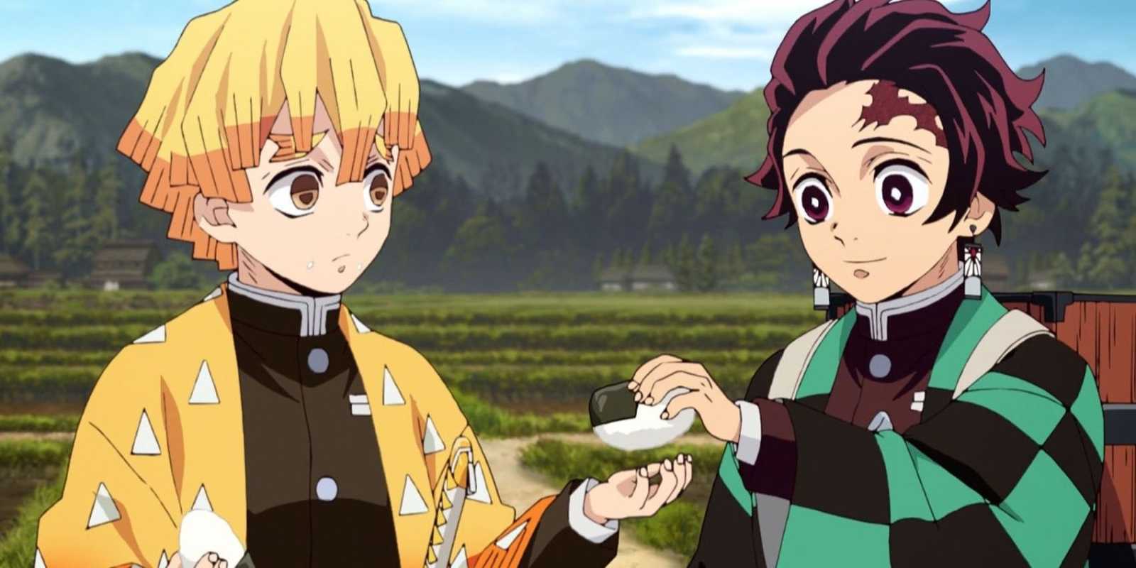 Tanjiro gibt Zenitsu vor einem Feld und Bergen ein Reisbällchen