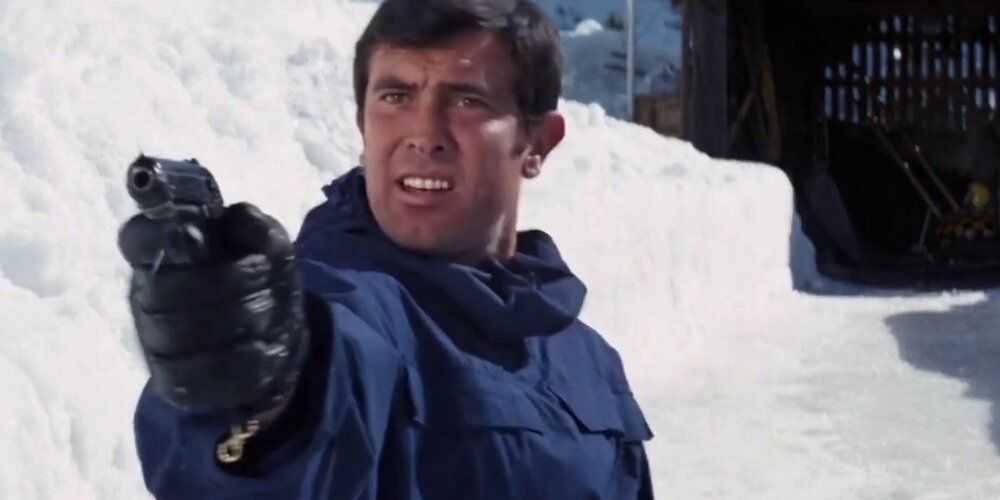 George Lazenby ako James Bond mieriaci zbraňou do snehu vo filme On Her Majesty