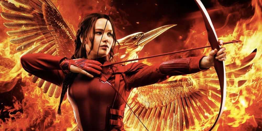 Katniss Everdeen sosteniendo un arco y una flecha frente a un Sinsajo en llamas