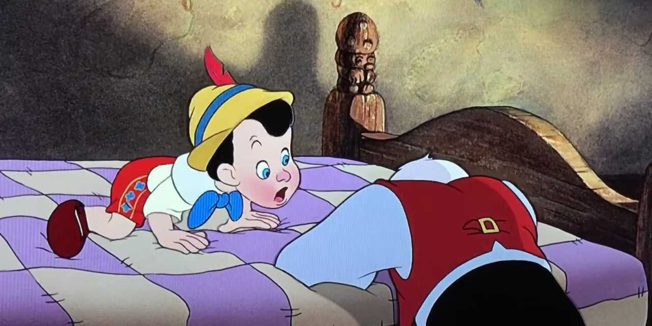 ベッドに座ってゼペットを見つめるピノキオ