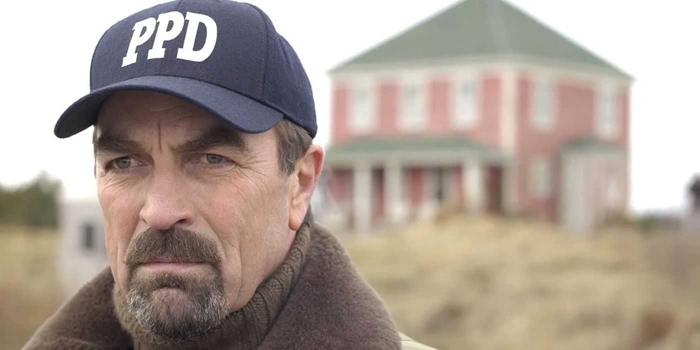 Jesse Stone con una gorra del departamento de policía frente a un edificio en Stone Cold