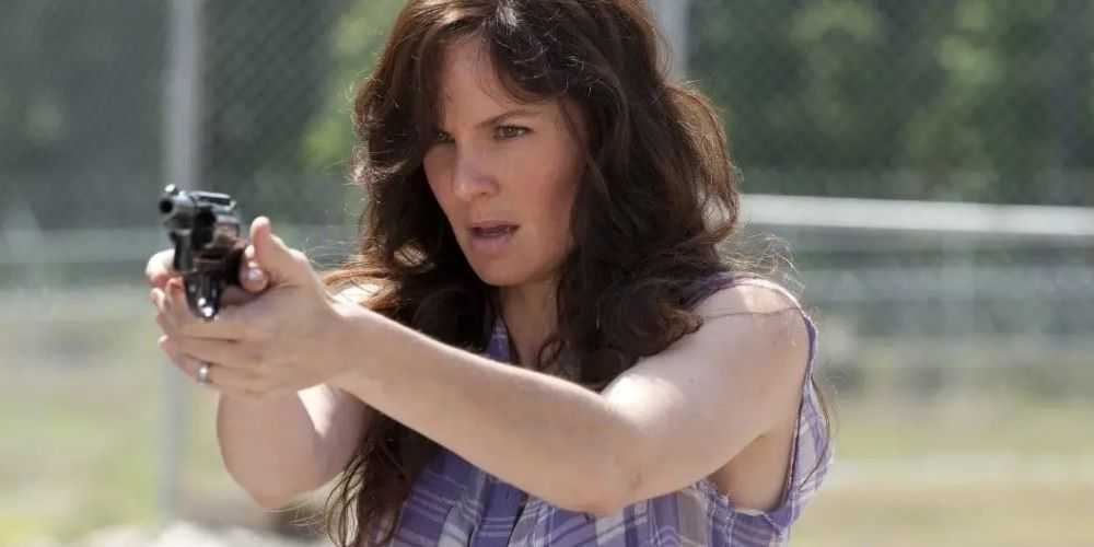 Lori Grimes hält in The Walking Dead eine Waffe auf einem Feld vor sich hin
