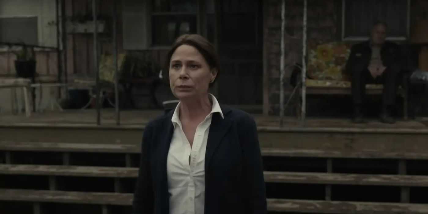 Maura Tierney parada afuera de una cabaña