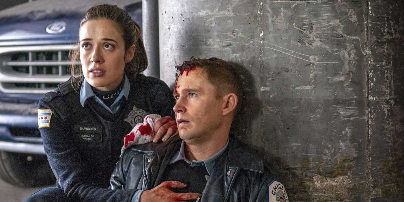 Marina Squerciati como Kim Burgess se agacha junto a Brian Geraghty como Sean Roman, quien recientemente recibió un disparo y está cubierto de sangre en el Departamento de Policía de Chicago.