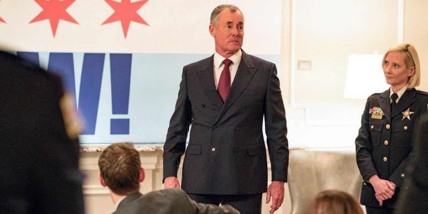 John C. McGinley como Brian Kelton está frente a una multitud con Anne Heche como Katherine Brennan detrás de él en Chicago P.D.